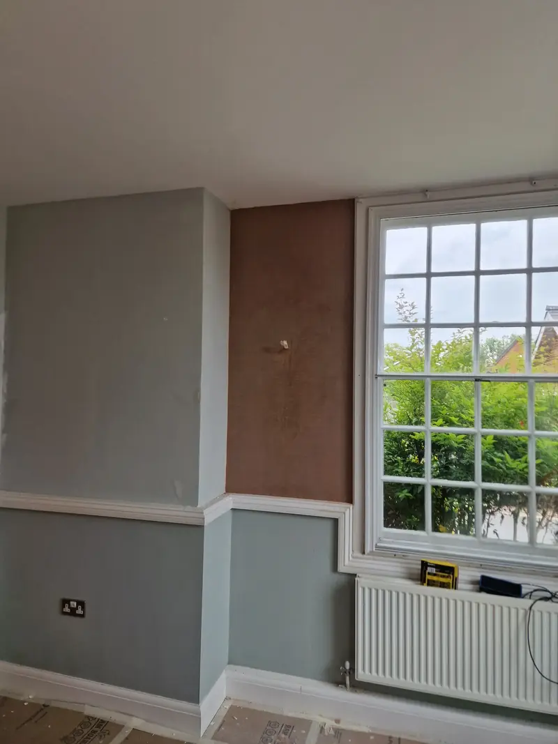 The Witham room part-way through the work, with a boarded wall section beside a sash window and radiator