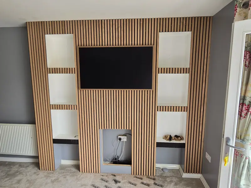 Slatted media wall with a recessed TV space and alcove shelving, built by our team in Colchester