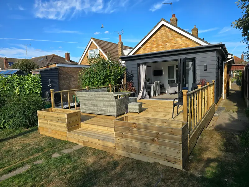 New raised timber deck with steps, built-in planters and a spindle balustrade behind a house in Clacton-on-Sea