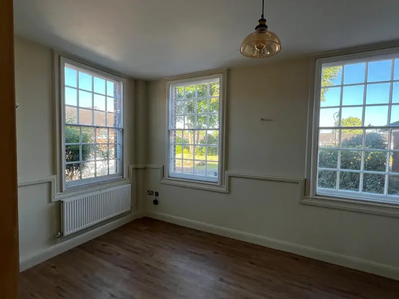 Refurbished room in Witham with three sash windows, cream walls, panel mouldings and a pendant light