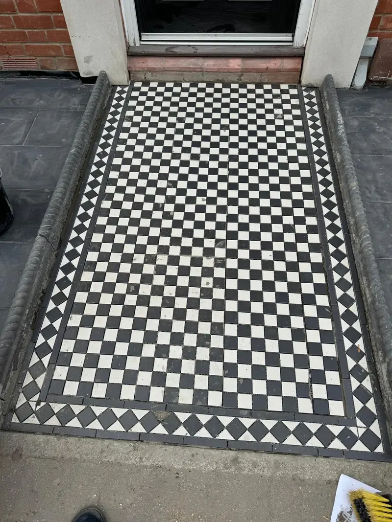 Close-up of a black and white chequered mosaic path with a diamond border and rope-top edging in Colchester
