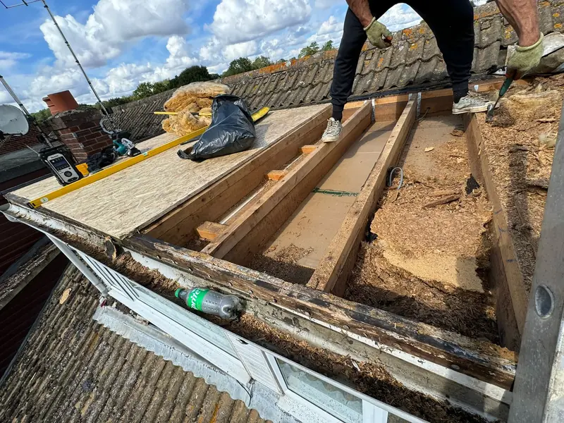 Old flat roof deck lifted to reveal rotten timber, with new joists and boards going in