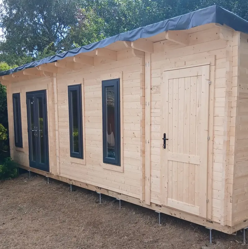 Finished timber garden office with dark grey windows, French doors and a side store door, raised on adjustable steel feet