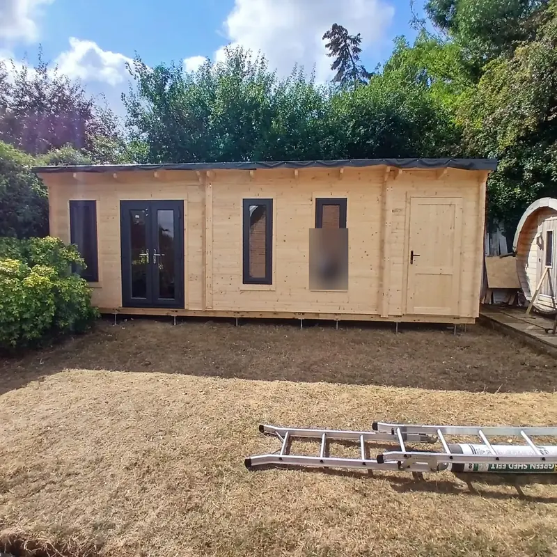 Finished pent roof log garden office with anthracite French doors, three tall windows and a store door, on steel feet